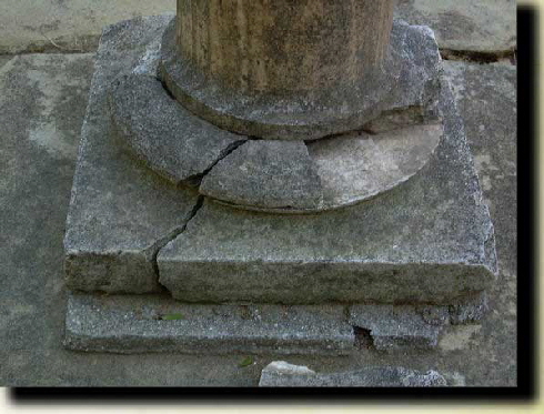 Damaged limestone pedestal - cracks and missing stone.